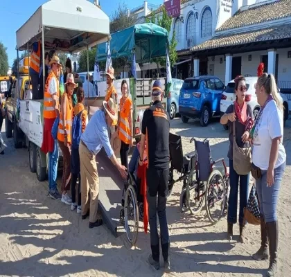 Varias personas voluntarias subiendo a una usuaria en silla de ruedas a un autobús turístico.