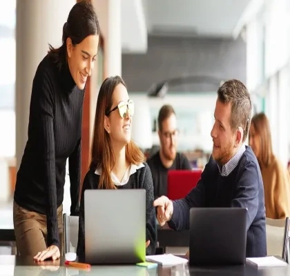 Tres personas hablando delante de la pantalla de un ordenador en la oficina