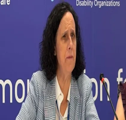 Ana Peláez delante de un micrófono en una sala de prensa, con un fondo azul de logos a su espalda