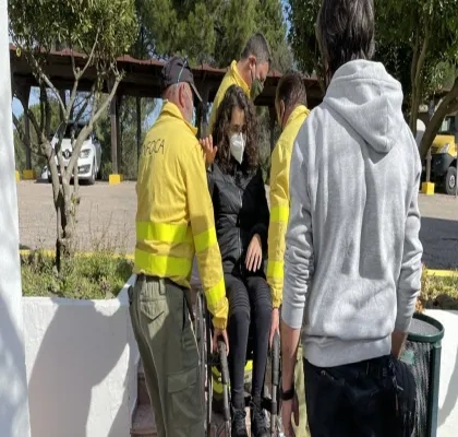 Tres técnicos de emergencias levantando a pulso a una usuaria en silla de ruedas, haciendo un ejemplo práctico con un supervisor que explica