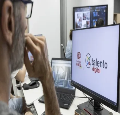 Un hombre con gafas mirando a la pantalla de un ordenador donde sale el logo de por talento digital y fundación once