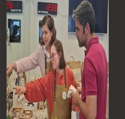 Dos profesores atendiendo a una alumna del CEE ACHIRA, enseñándola a vender en el mercadillo