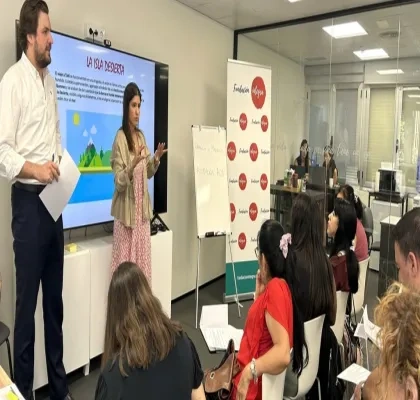 Dos profesores dando una explicación a sus alumnas, que están sentadas en sus pupitres