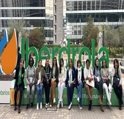Doce mujeres que formaron parte del programa sentadas delante del logo de Iberdrola en sus oficinas centrales
