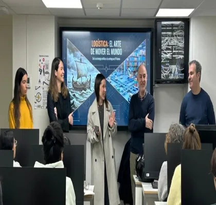 Varios formadores del taller impartiendo indicaciones frente a los alumnos, con el proyector de fondo presentando una diapositiva