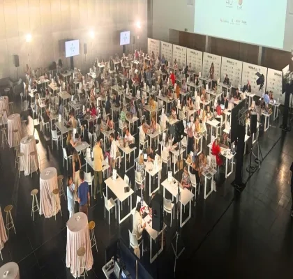 Salón de juntas con varias mesas y muchos ponentes y oyentes