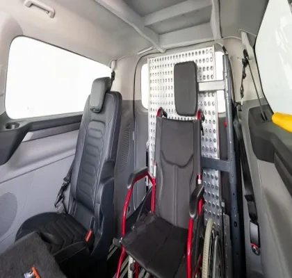 Interior de la furgoneta en la que se ve un asiento y otros reclinados para que quepa la silla de ruedas que hay en el medio