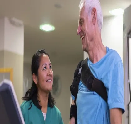 Un señor mayor siendo tratado por una mujer rehabilitadora
