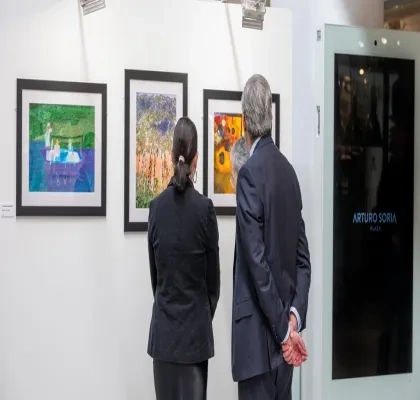 Dos personas observando un cuadro en una exposición