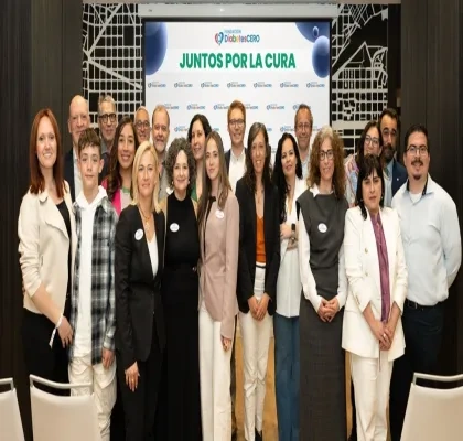 Veinte personas posando para la foto junto delante de la pantalla digital donde se proyectan diapositivas del encuentro