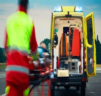 Un profesional del servicio de emergencias traslada a un paciente en camilla hasta una ambulancia
