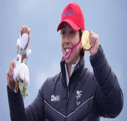 La galardonada sujetando la medalla y el muñeco oficial en el podium