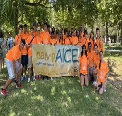 Posado de todos los participantes del campamento, sujetando una bandera con el logo CampAICE