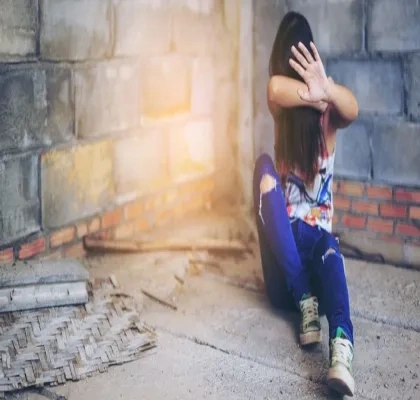 Mujer joven tapándose la cara en un edificio en ruinas