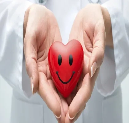 medico sosteniendo un corazón de juguete con una sonrisa dibujada