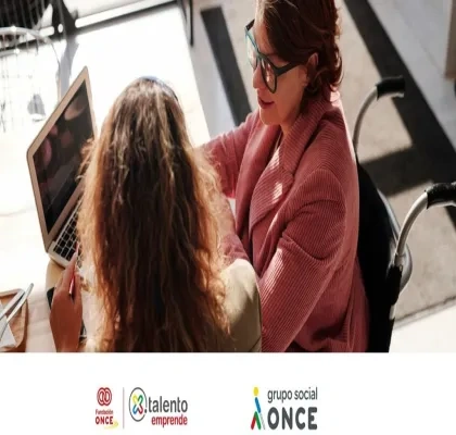 Dos mujeres, una con discapacidad, mirando a la pantalla del ordenador mientras trabajan