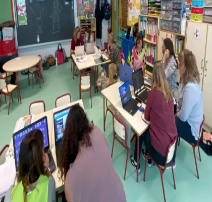 Ocho profesoras mirando ordenadores en un aula infantil