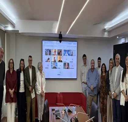 Participantes del grupo de la reunión con una pantalla digital en la que estaban proyectando una sesión virtual con otros participantes