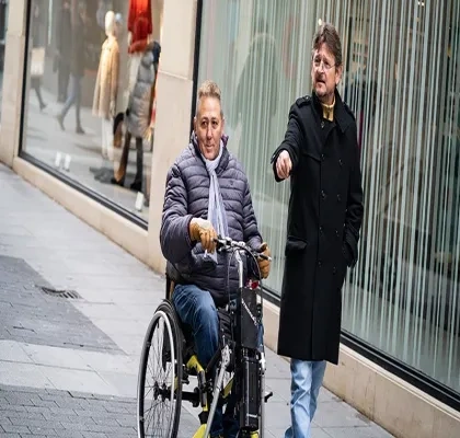 Un asistente personal al lado de un hombre en silla de ruedas