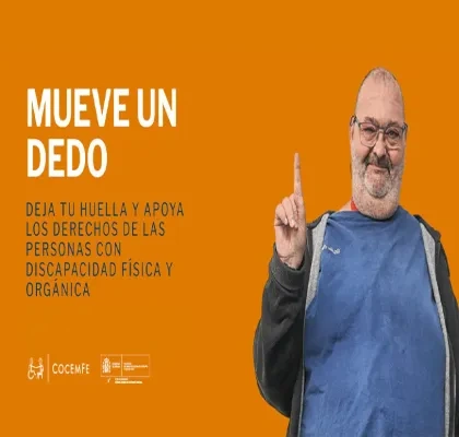 Hombre sonriente levantando el dedo índice frente a un fondo naranja en la campaña “Mueve un Dedo” de COCEMFE.