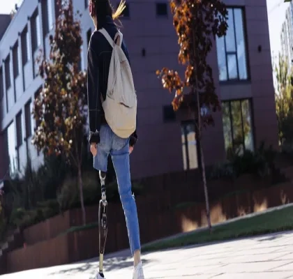 Mujer joven con una amputación caminando por un campus universitario