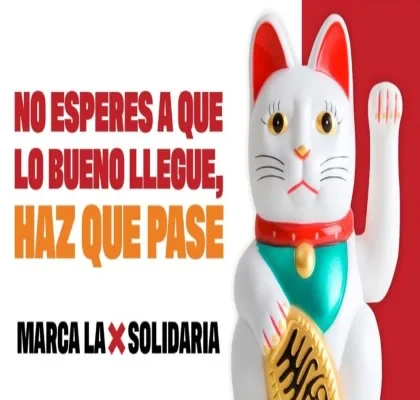 Imagen con fondo blanco y rojo en la que aparece un maneki-neko (gato de la suerte japonés) blanco con detalles rojos, verdes y dorados, levantando una pata. A la izquierda se lee el texto en mayúsculas: “NO ESPERES A QUE LO BUENO LLEGUE, HAZ QUE PASE. MARCA LA X SOLIDARIA”.