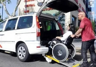 Un taxista ayuda a entrar en su vehículo a una cliente en silla de ruedas | Foto del Ayuntamiento de Madrid
