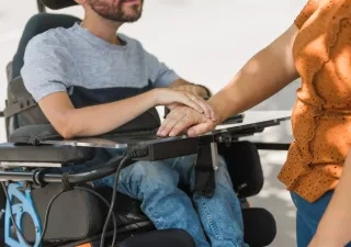 Persona en silla de ruedas junto a cuidadora 