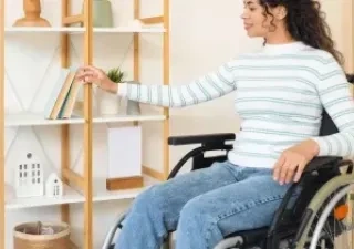mujer con una silla de ruedas colocando un libro en una estanteria