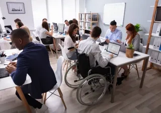 Un técnico en silla de ruedas comparte espacio de trabajo en una oficina colaborativa 