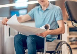 Un hombre en silla de ruedas con unos documentos en la mano