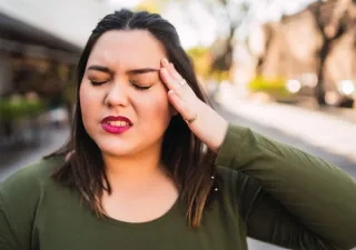 Una mujer se toca la cabeza por una migraña