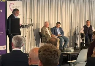 Los ponentes subidos en el escenario del evento, con un moderador en el atril y a su espalda el cartel de AccesibleEU