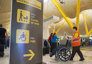 Un operario del Servicio de Asistencia a Personas con Discapacidad o Movilidad Reducida, 'Sin Barreras', de Aena, llevando una silla de ruedas (Fuente: Aena)