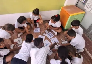 Varios alumnos en círculo mientras juegan y aprenden con pictogramas en el centro