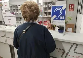 mujer mayor con discapacidad auditiva cerca del bucle magnético de la oficina de Avanza