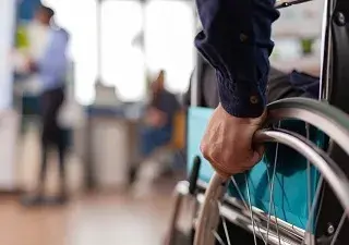 Una persona en silla de ruedas entrando en una sala (Fuente: Servimedia)