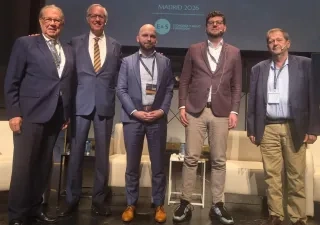 Cinco ponentes posan sobre el escenario de la Convención Europea de la Dependencia 2026, celebrada en Madrid. Detrás de ellos se observa una pantalla con el nombre del evento y varios logotipos institucionales. En el escenario hay sillones blancos y mesas auxiliares, en un espacio preparado para una mesa de debate sobre el futuro de los cuidados de larga duración, la atención sanitaria y la dependencia en Europa.