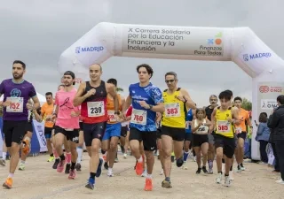 Salida de la X Carrera Solidaria por la Educación Financiera y la Inclusión en el Parque Forestal de Valdebebas (Madrid), con decenas de corredores atravesando el arco de meta de una prueba organizada por ASNEF y Fundación ONCE.