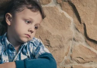 Un niño sentado apoyado en un muro