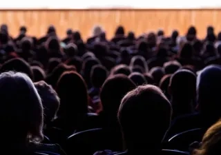 Siluetas de personas de espalda mirando una funcion teatral