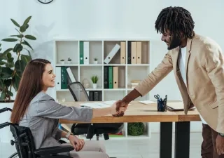 persona en silla de ruedas dando apretón de manos a un hombre con traje