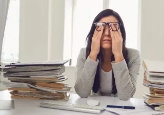 Mujer llevándose las manos a los ojos debido al agotamiento visual del trabajo