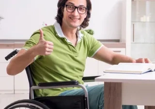 Joven estudiante con discapacidad con el libro en el escritorio