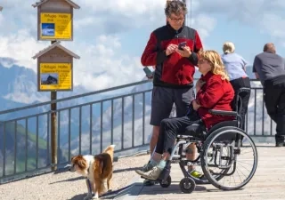 Una pareja con su perro, ella en silla de ruedas, disfrutando de un turismo en la montaña