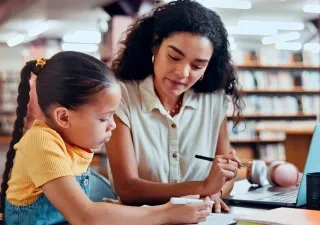 Una mujer con una niña haciendo una tarea