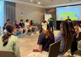 Varios jóvenes disfrutando de un coloquio, en círculo delante de los ponentes