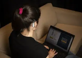 Una persona con discapacidad auditiva mirando en un portátil un documento de productos de apoyo de FIAPAS (Fuente: FIAPAS)