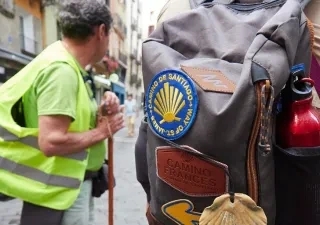 un peregrino durante el Camino de Santiago con un chaleco reflectante y una mochila