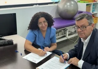 Acto de firma del acuerdo de donación entre Donoso y la jefa de rehabilitación del centro.